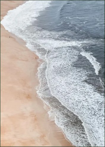 Waves meeting a sandy shoreline from above